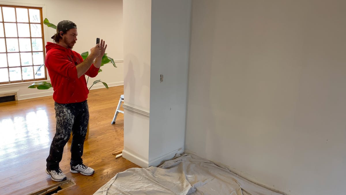 A professional residential painter takes a photo of a wall to show progress of his work
