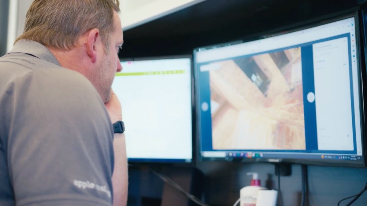 Project manager reviews framing inspection photo on desktop construction management software.